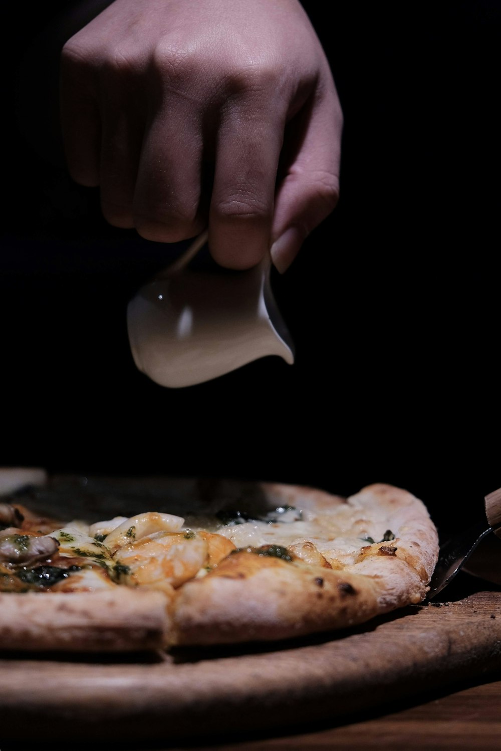 person holding silver fork and knife slicing pizza