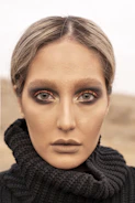 Close-up of a model with subtle gold makeup against a charcoal background.