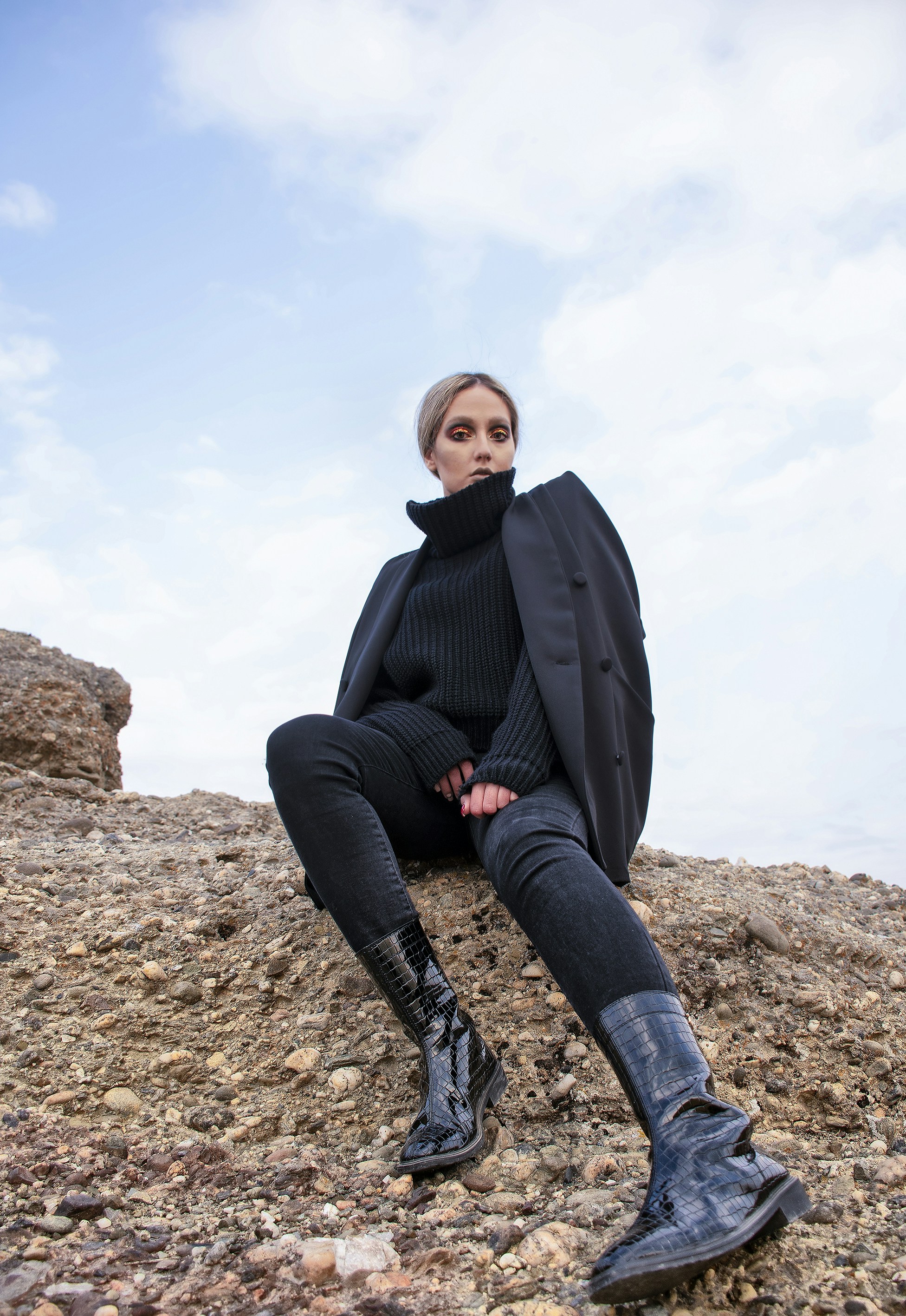 Hombre con chaqueta negra sentado en roca marrón durante el día