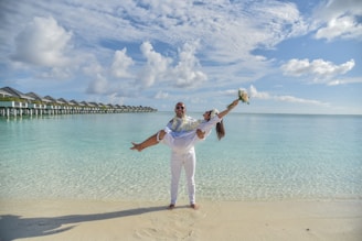 girl in white shirt and white pants standing on beach shore during daytime