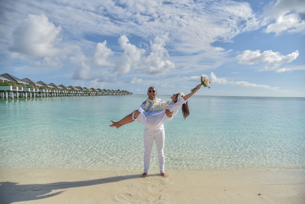 girl in white shirt and white pants standing on beach shore during daytime