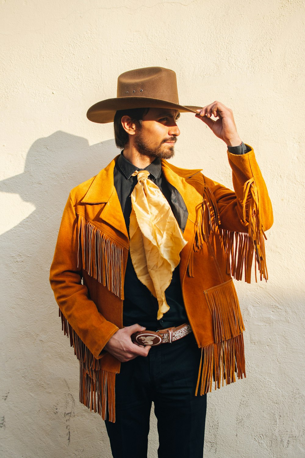 uomo in cappotto marrone e nero che indossa un cappello da cowboy marrone