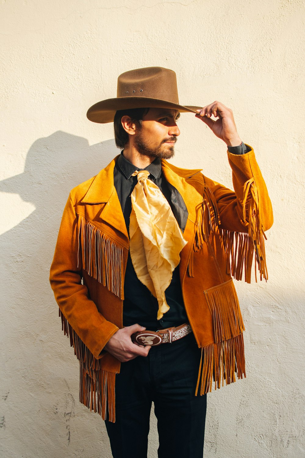 homme en manteau marron et noir portant un chapeau de cow-boy marron