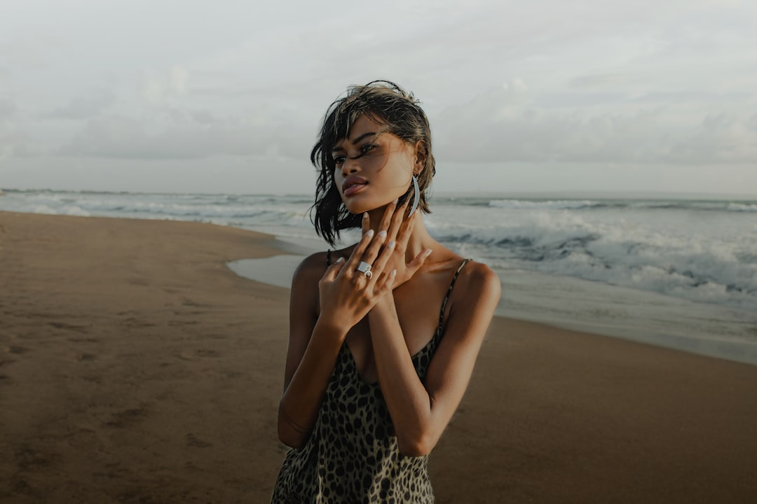 woman in black and white leopard print tank top standing on beach during daytime