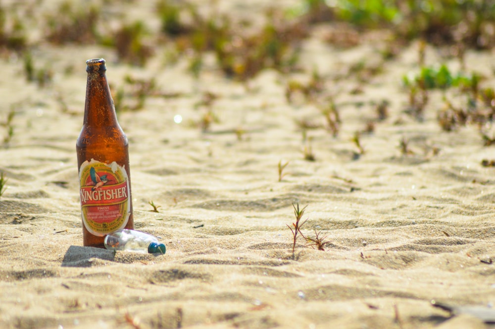 brown and white labeled bottle on sand