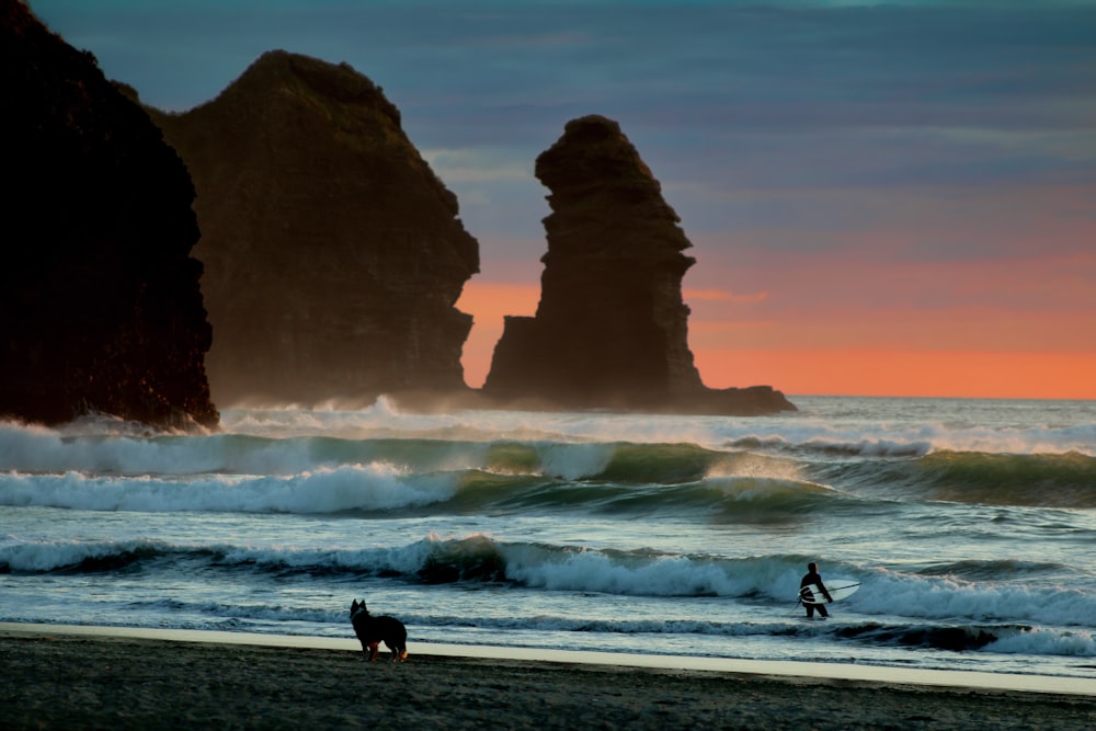 Silhouette de 2 personnes marchant sur la plage au coucher du soleil