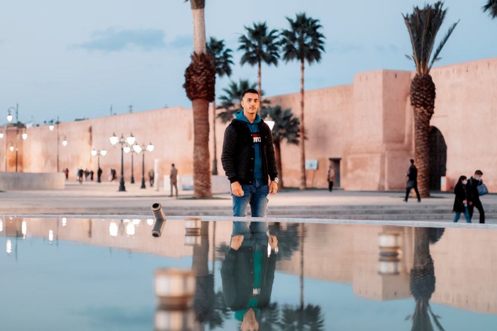 man in black jacket standing near palm tree during daytime