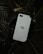 A white Blackberry smartphone is nestled among dark green palm leaves, creating a contrast between technology and nature.
