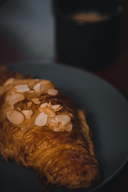 Freshly baked almond croissants arranged on a rustic ceramic plate.