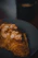 A close-up of a golden almond croissant with powdered sugar dusting on a rustic wooden table.