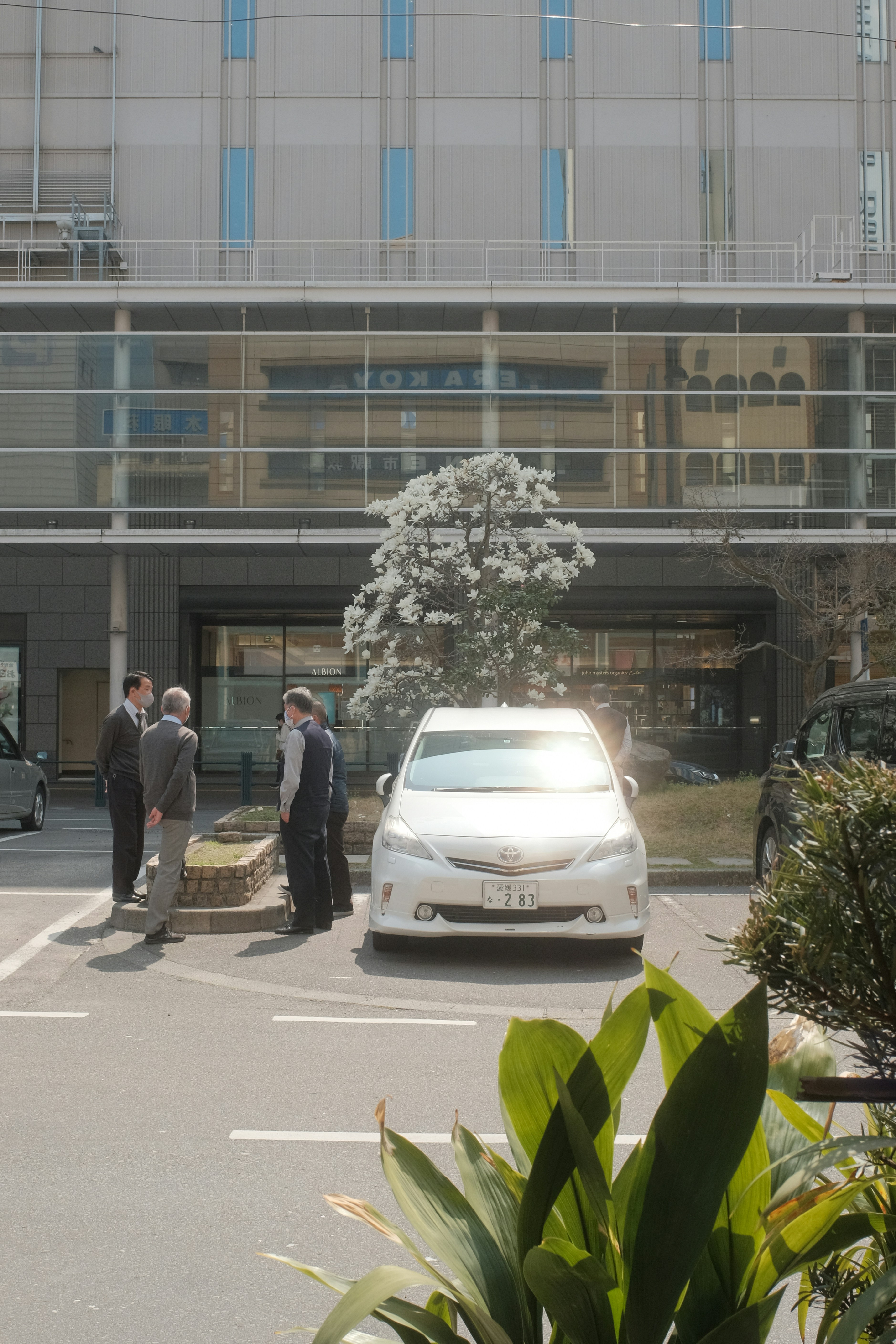 man in black jacket standing beside white car