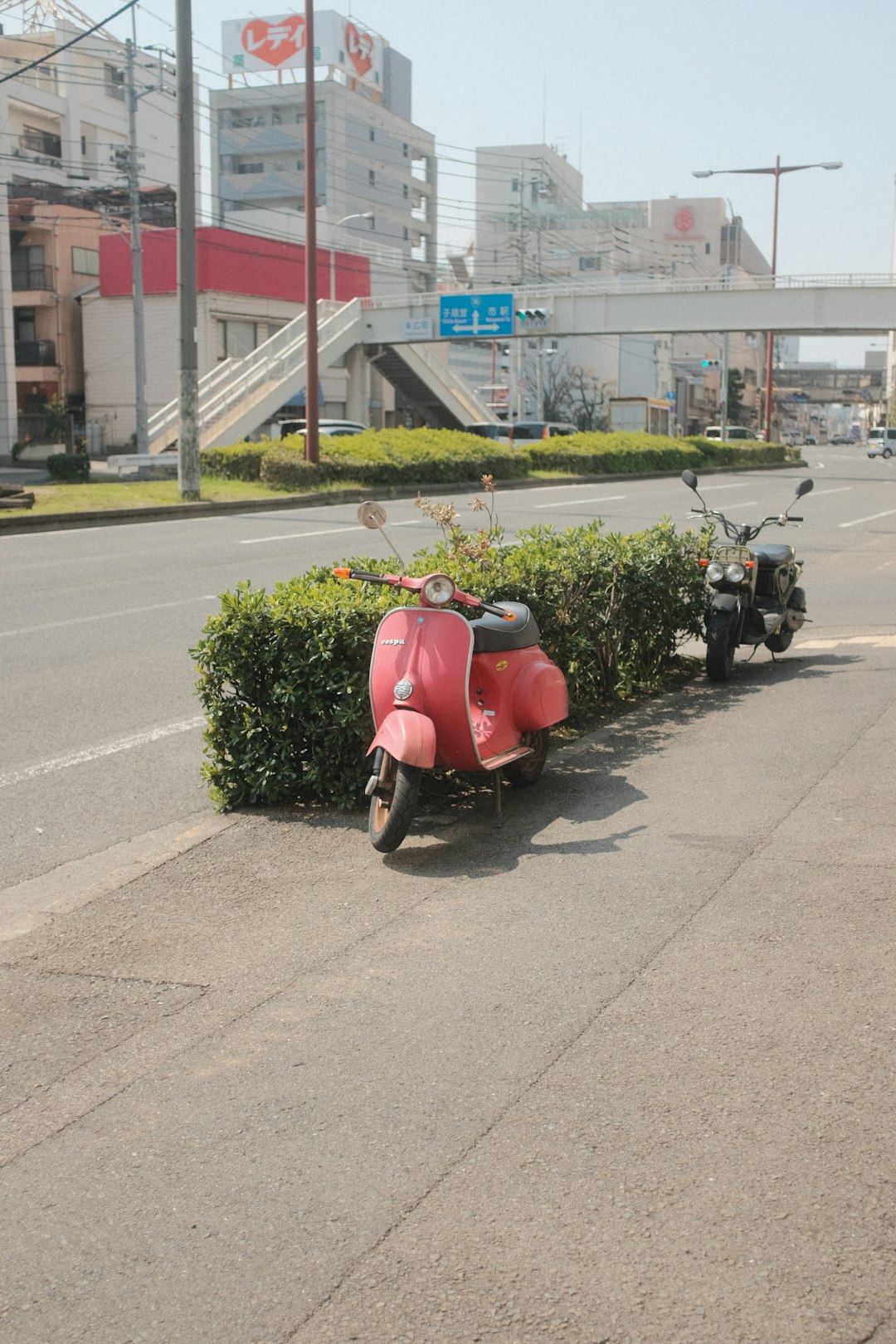 red and black motor scooter parked on sidewalk during daytime