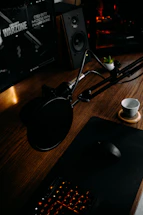 A cozy desk setup with a laptop, a microphone, and horror game posters on the wall.
