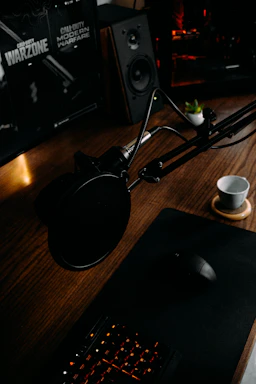 A cozy desk setup with a laptop, a microphone, and horror game posters on the wall.