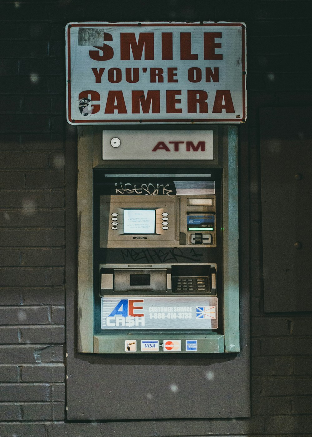 uma máquina de caixa eletrônico com uma placa que diz sorria que você está na câmera