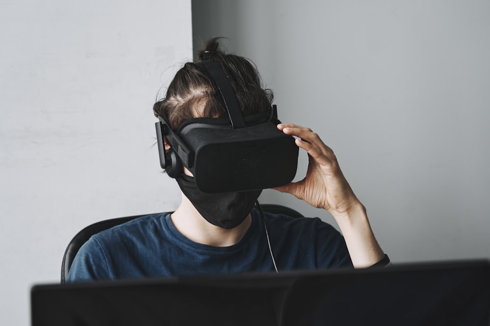 Homme en chemise bleue à col rond portant des lunettes VR noires