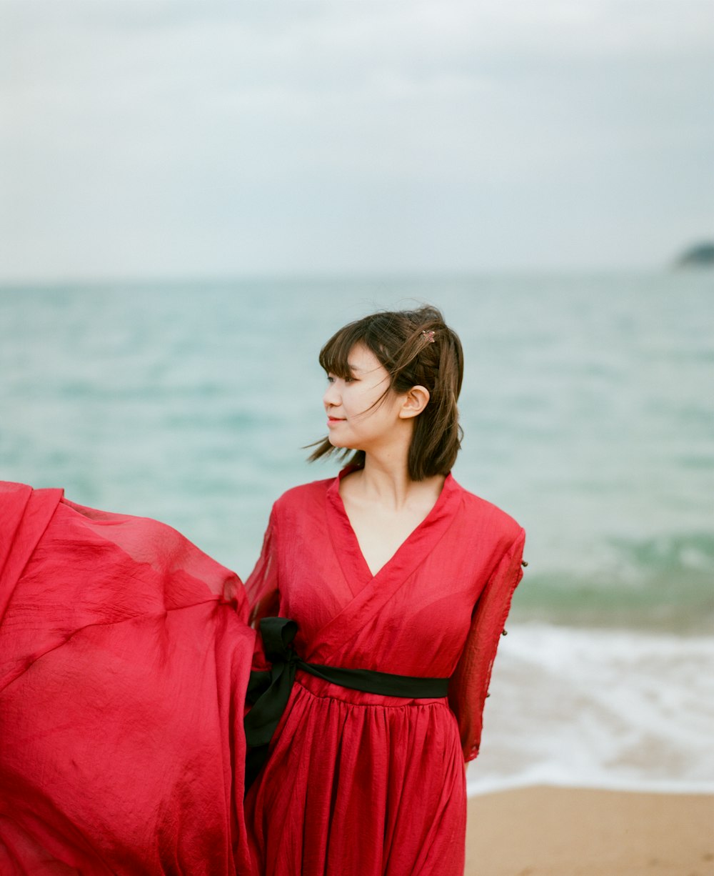 Foto mujer con vestido rojo de manga larga parada en la playa durante el  día – Imagen Fotografía de película gratis en Unsplash