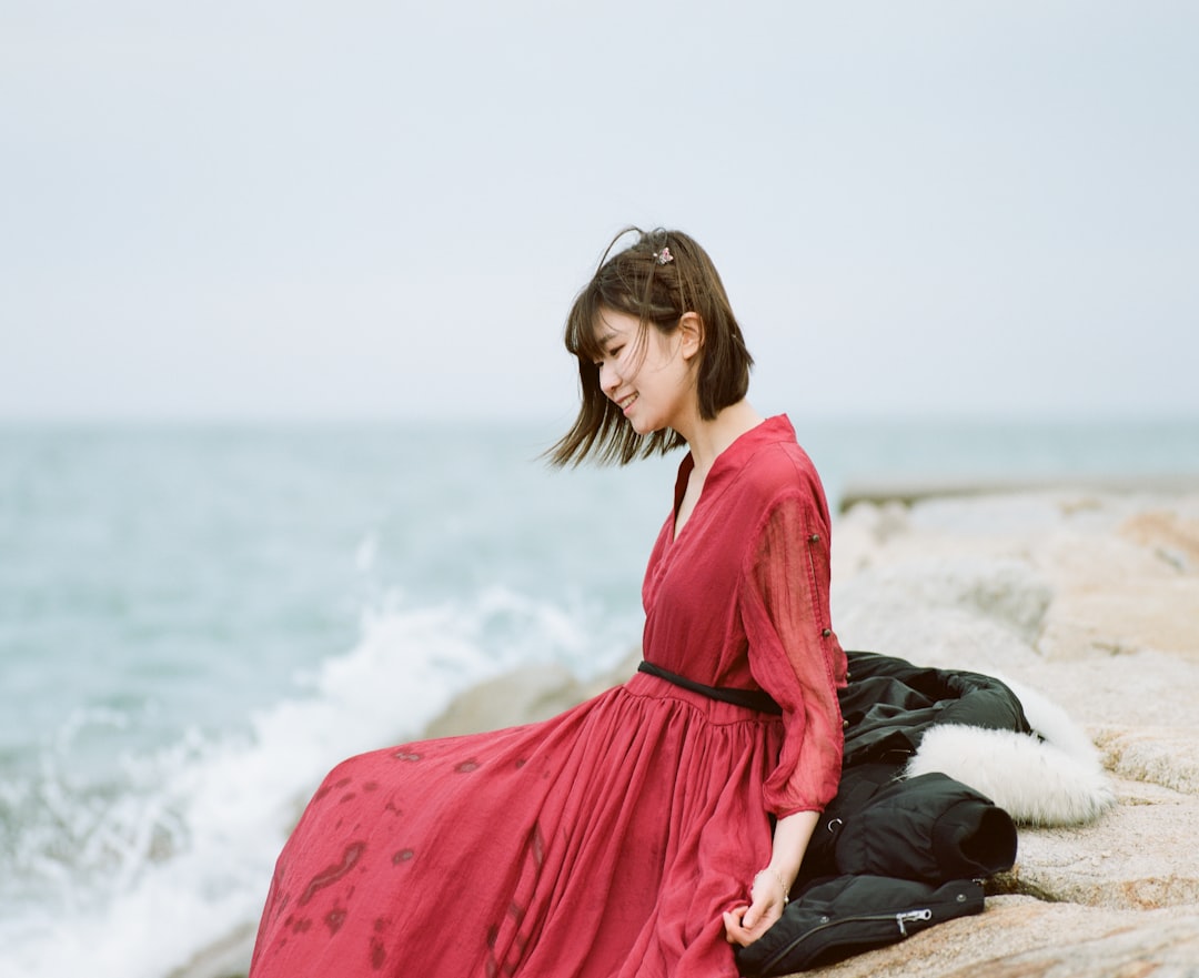 woman in red long sleeve dress sitting on black textile