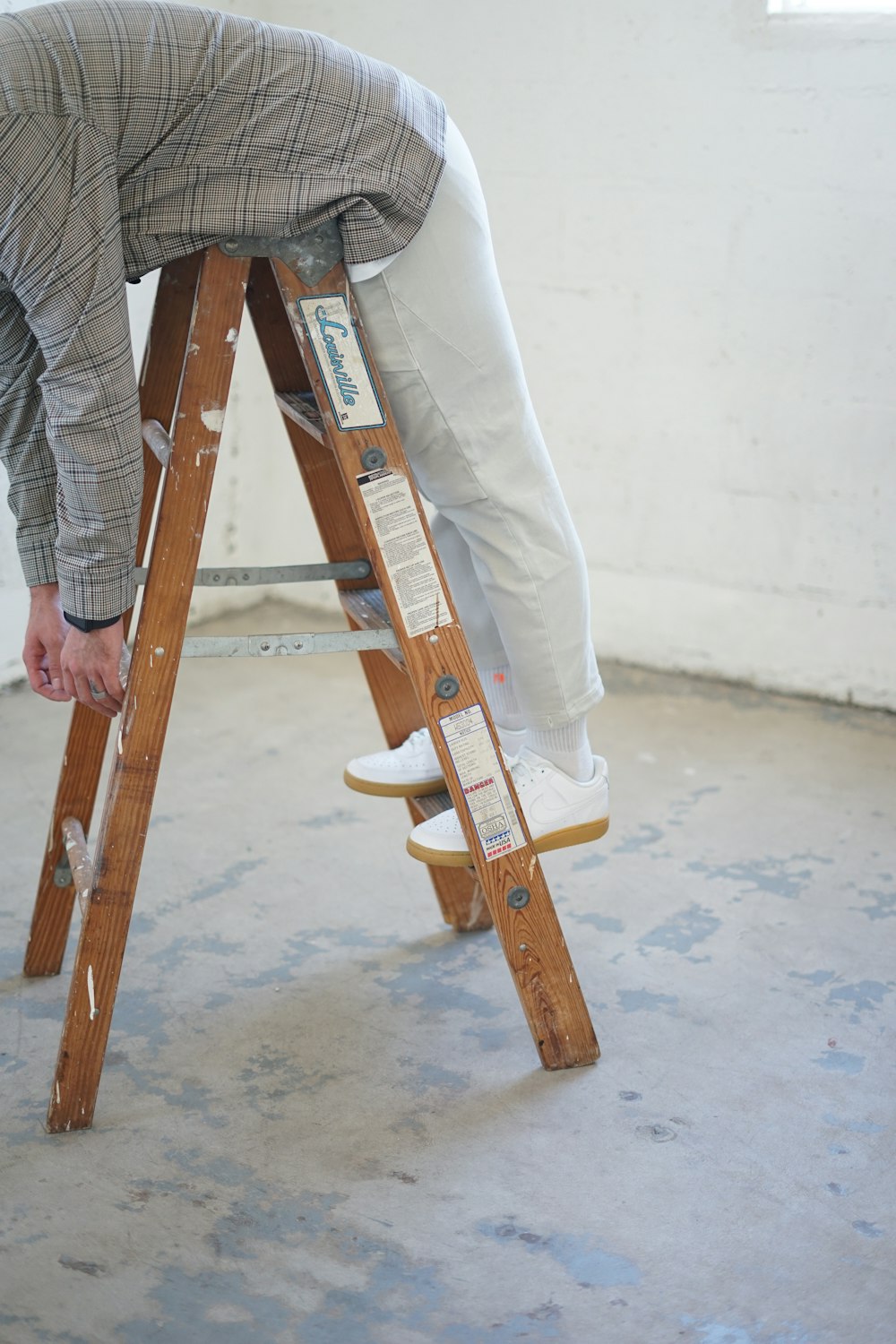 person in gray and white plaid dress shirt and blue denim jeans holding brown wooden skateboard