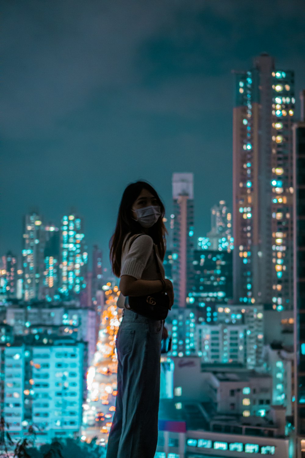 woman in black long sleeve shirt and blue pants standing on top of building during night