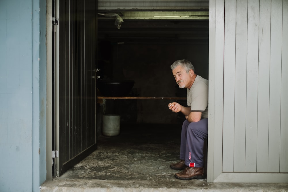 man in white long sleeve shirt and blue pants standing beside door