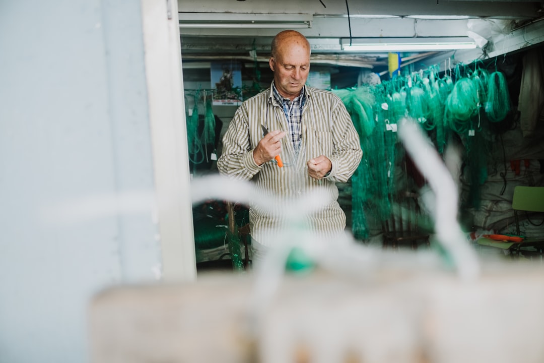 man in white and black stripe button up shirt standing near glass window