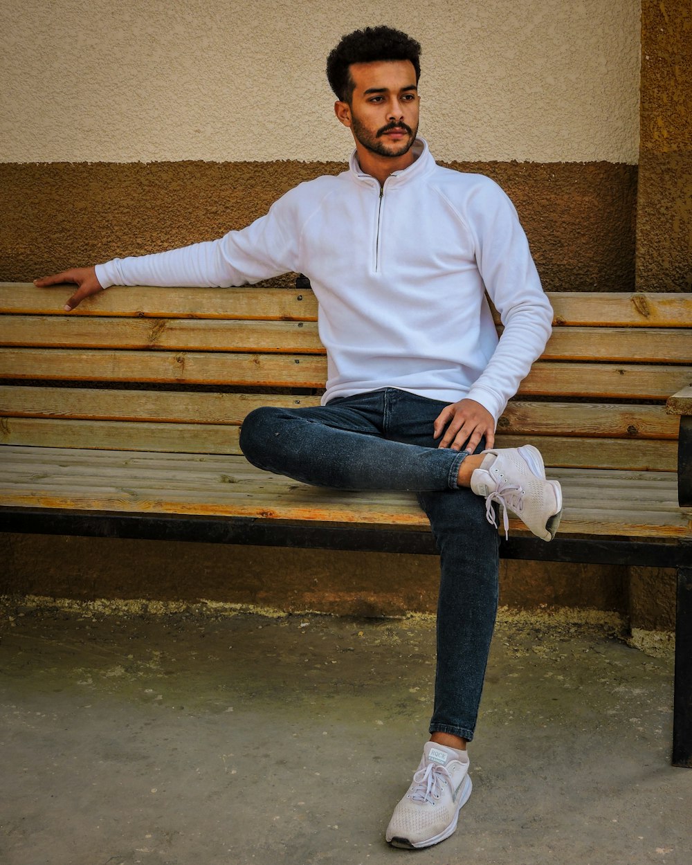 man in white sweater sitting on brown wooden bench