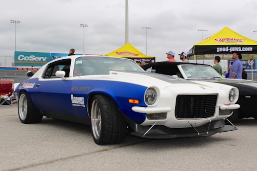 A vibrant red, white, and blue themed car show board featuring a classic American muscle car.
