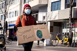 climate activist holding a sign that says "support your local planet"