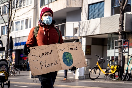 climate activist holding a sign that says "support your local planet"