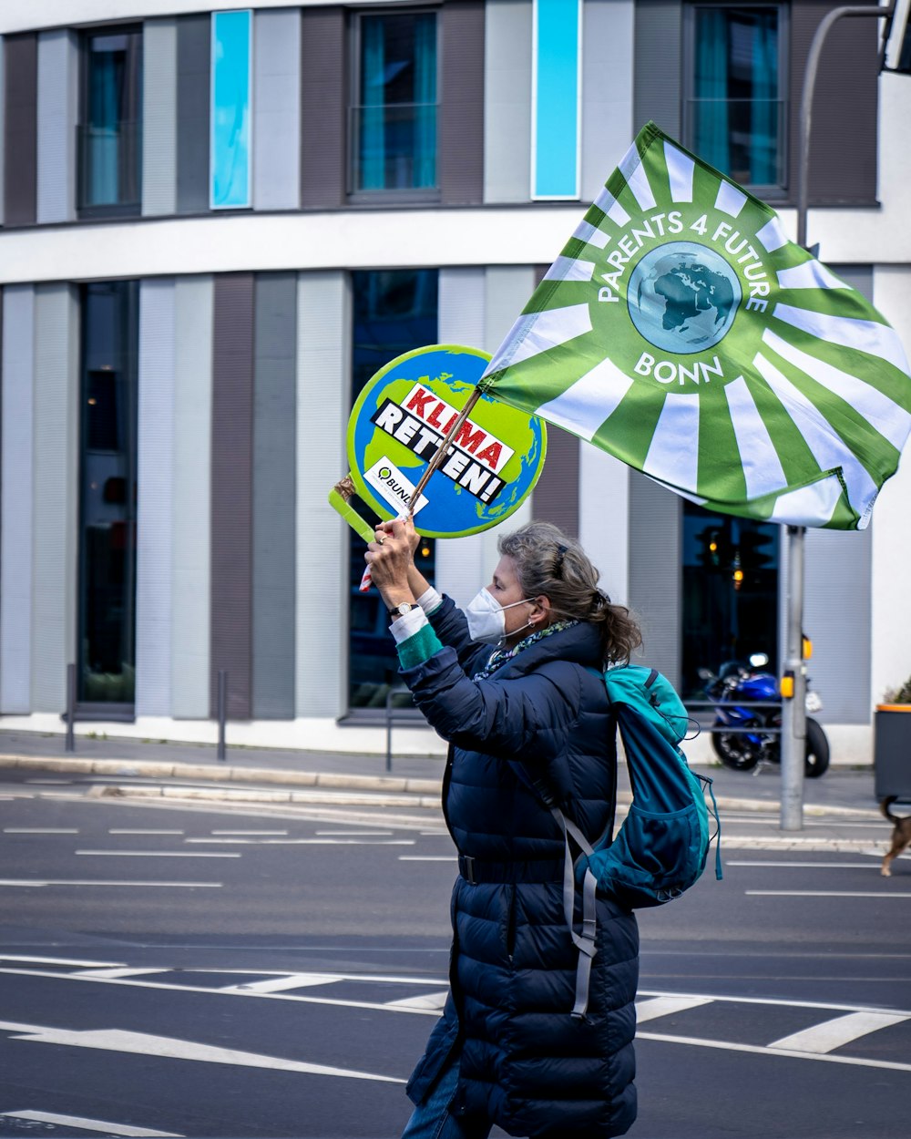 Femme en veste bleue tenant un parapluie jaune et vert