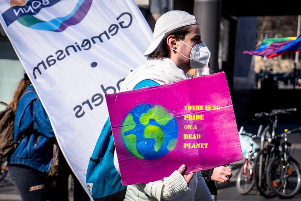 man in white jacket holding purple and white banner