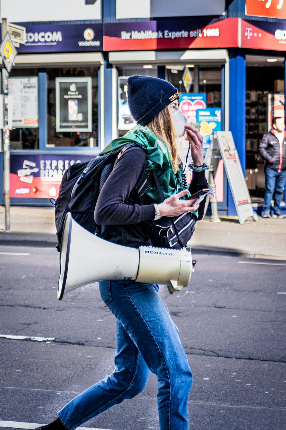 woman in black jacket and blue denim jeans holding smartphone