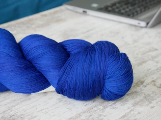A cozy workspace with colorful yarns and a laptop showing the Joycraft yarn tracking app.