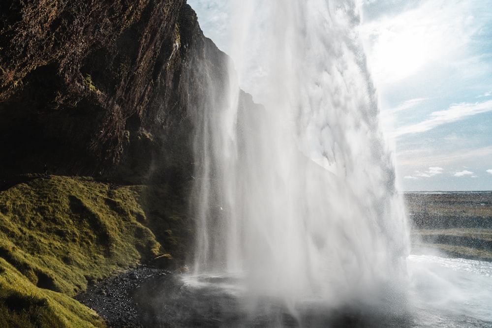 green grass on brown rock formation near waterfalls during daytime