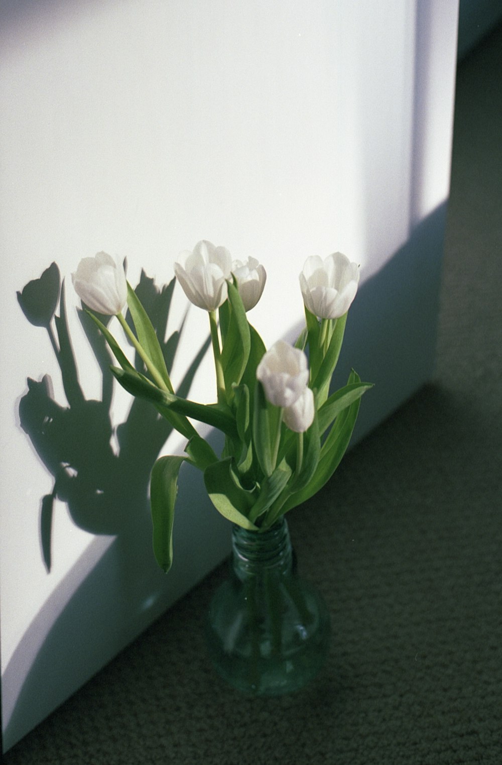 fleurs blanches sur vase en verre vert