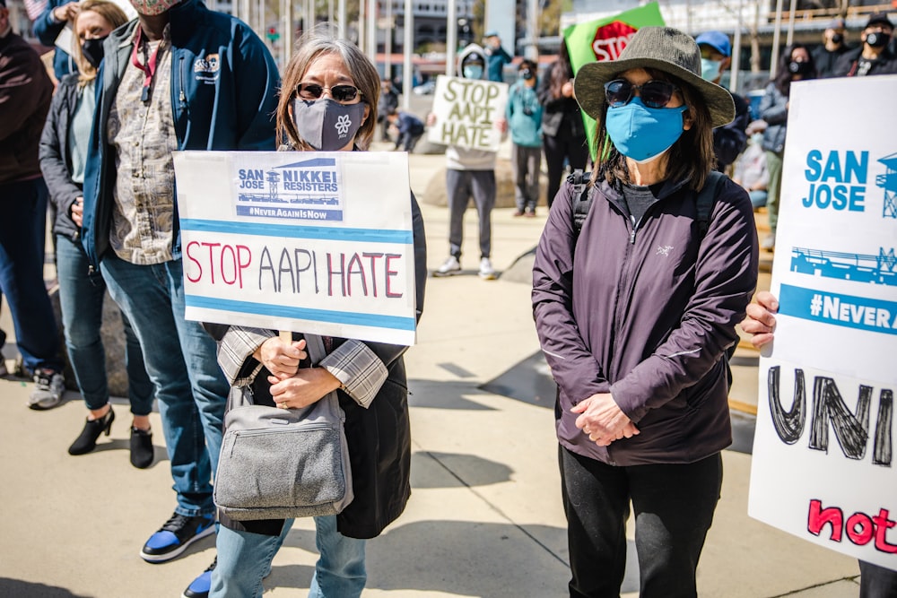 man in black jacket holding white and blue signage