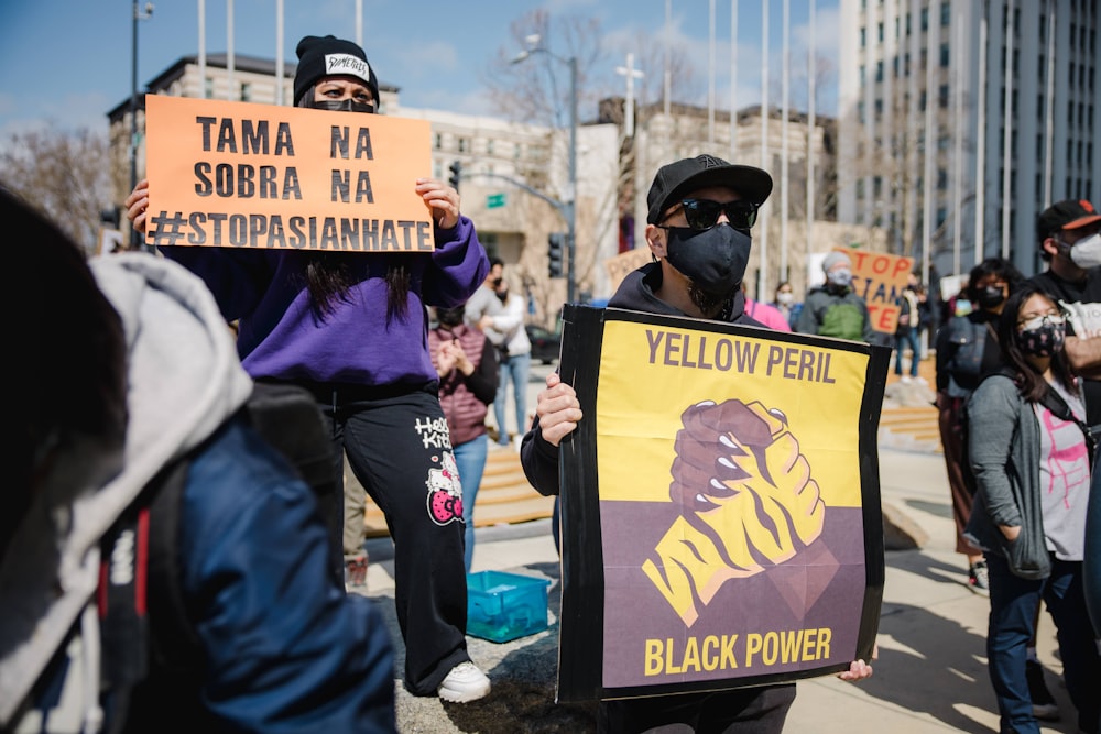 man in blue jacket holding black and yellow signage