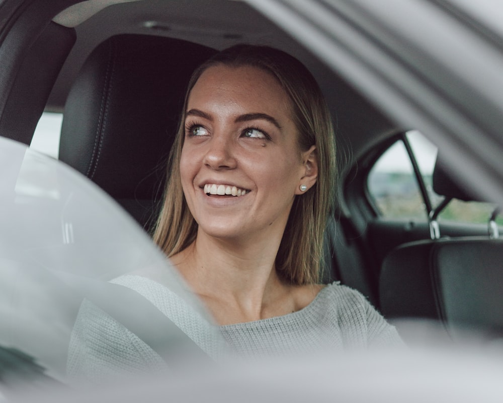smiling woman in white shirt inside car
