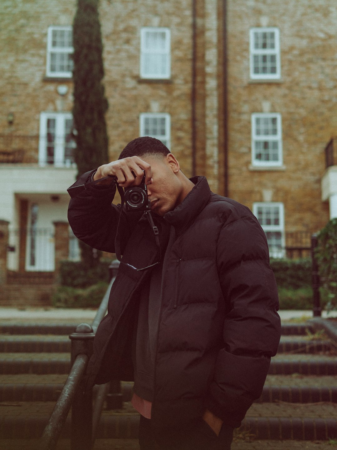 man in brown coat holding black camera