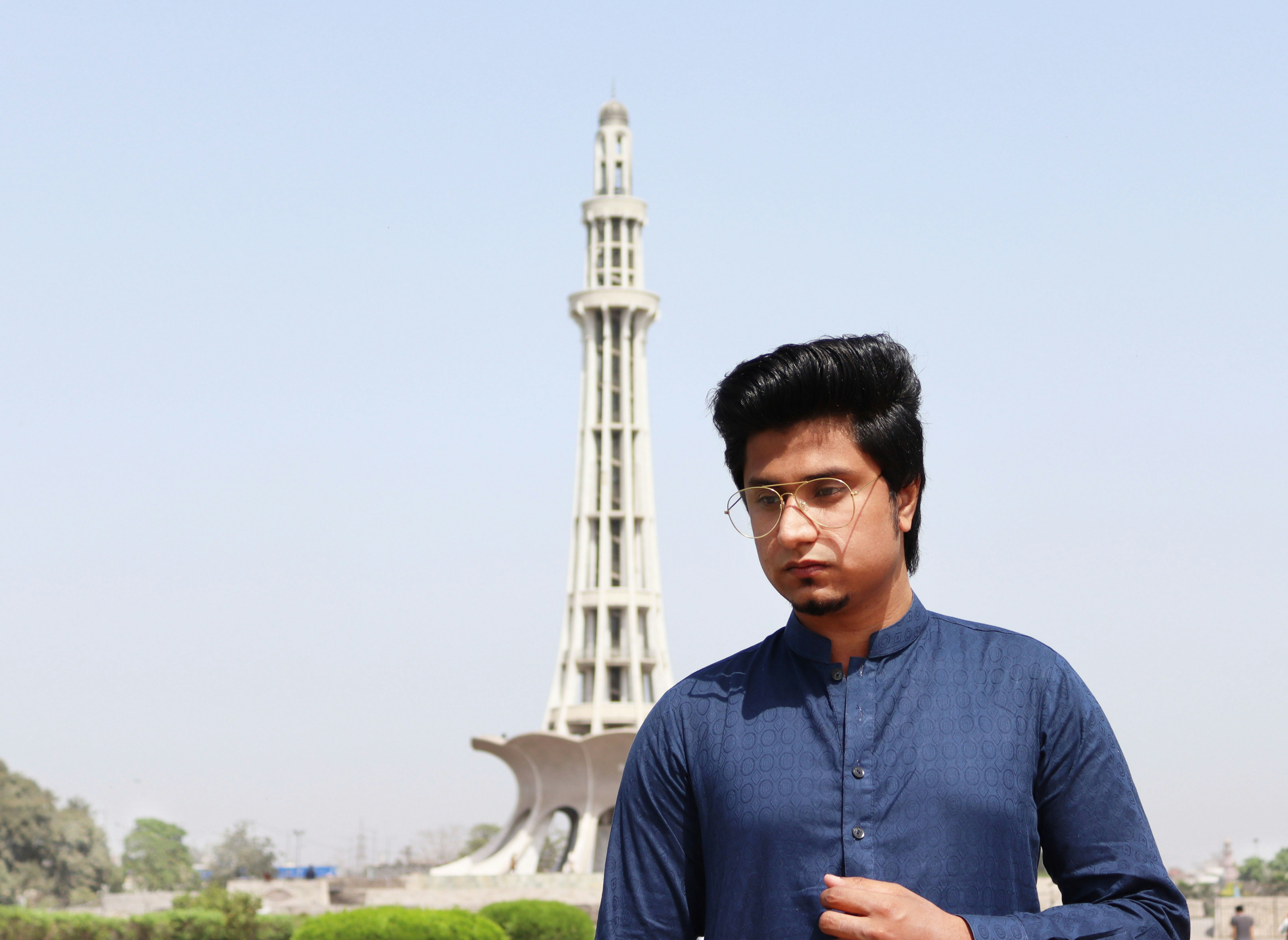 man in blue and black crew neck shirt standing near white concrete tower during daytime