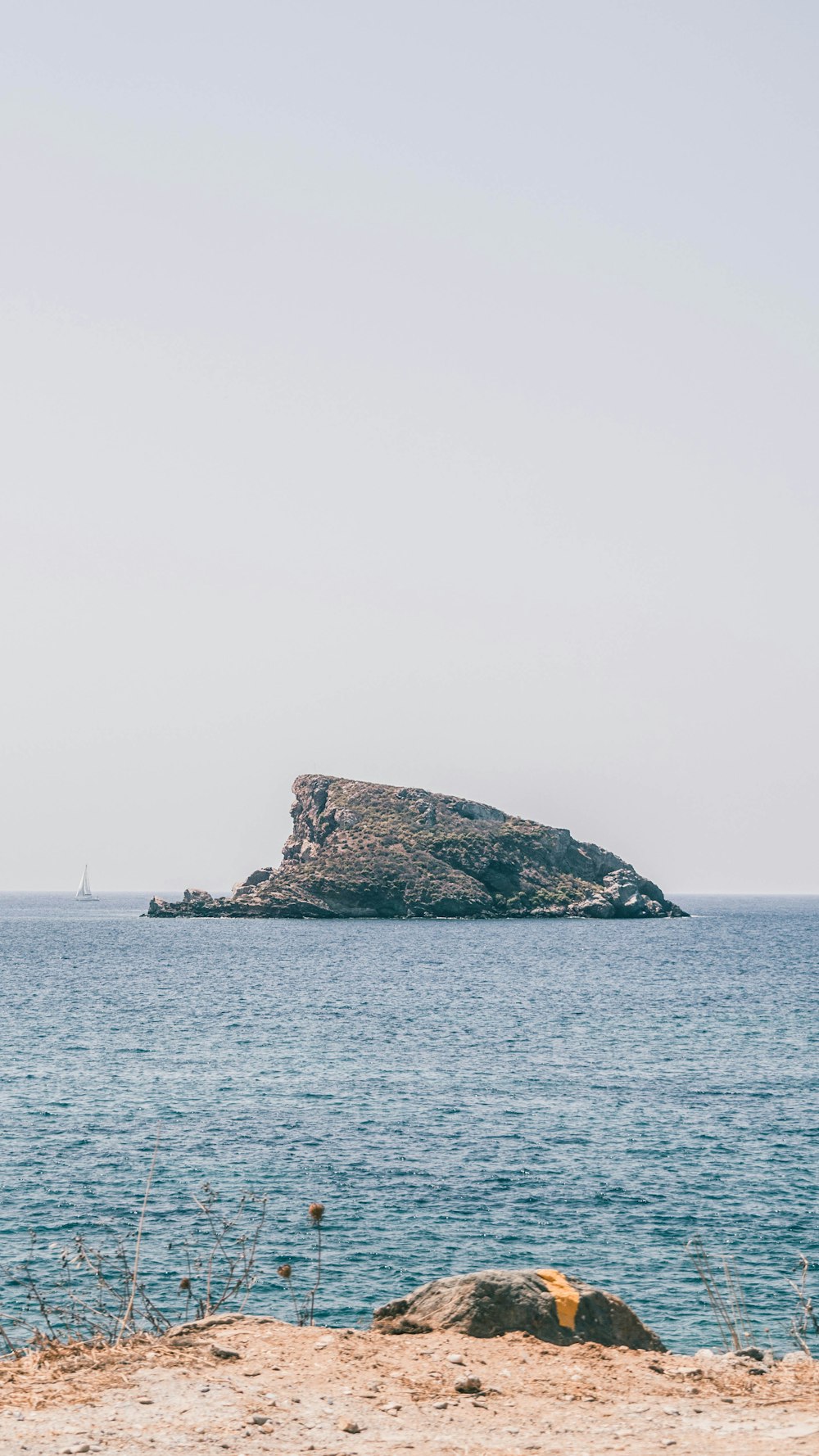 brown and green rock formation on sea under white sky during daytime