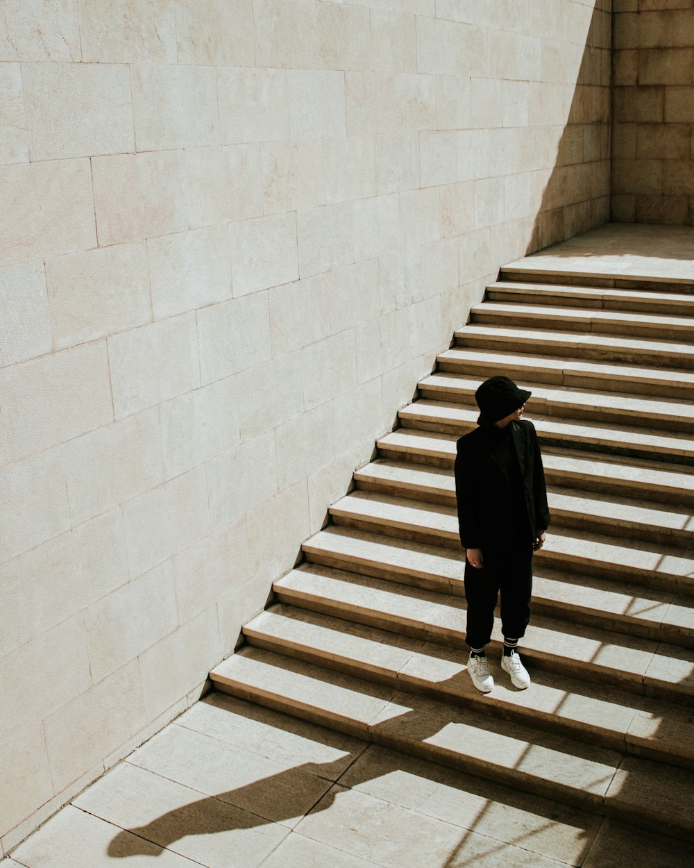 femme en robe noire à manches longues marchant sur un escalier en béton blanc