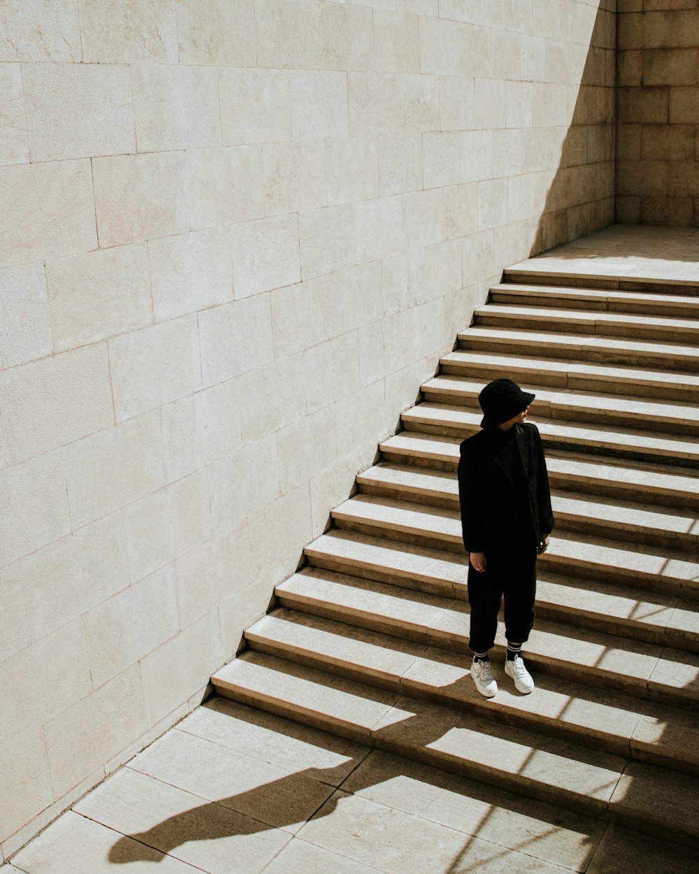 woman in black long sleeve dress walking on white concrete staircase