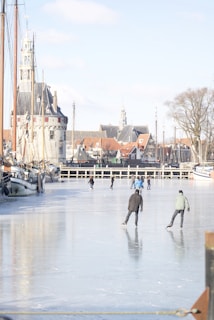 A picturesque Amsterdam canal in winter with people gracefully ice skating on natural ice.
