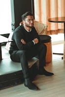 man in black dress shirt sitting on brown chair