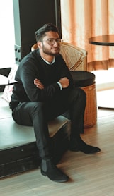 man in black dress shirt sitting on brown chair