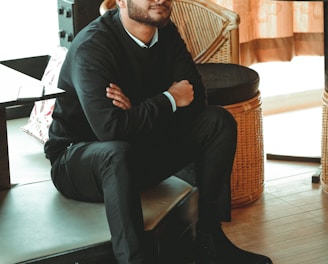 man in black dress shirt sitting on brown chair