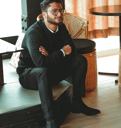 man in black dress shirt sitting on brown chair