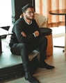 man in black dress shirt sitting on brown chair